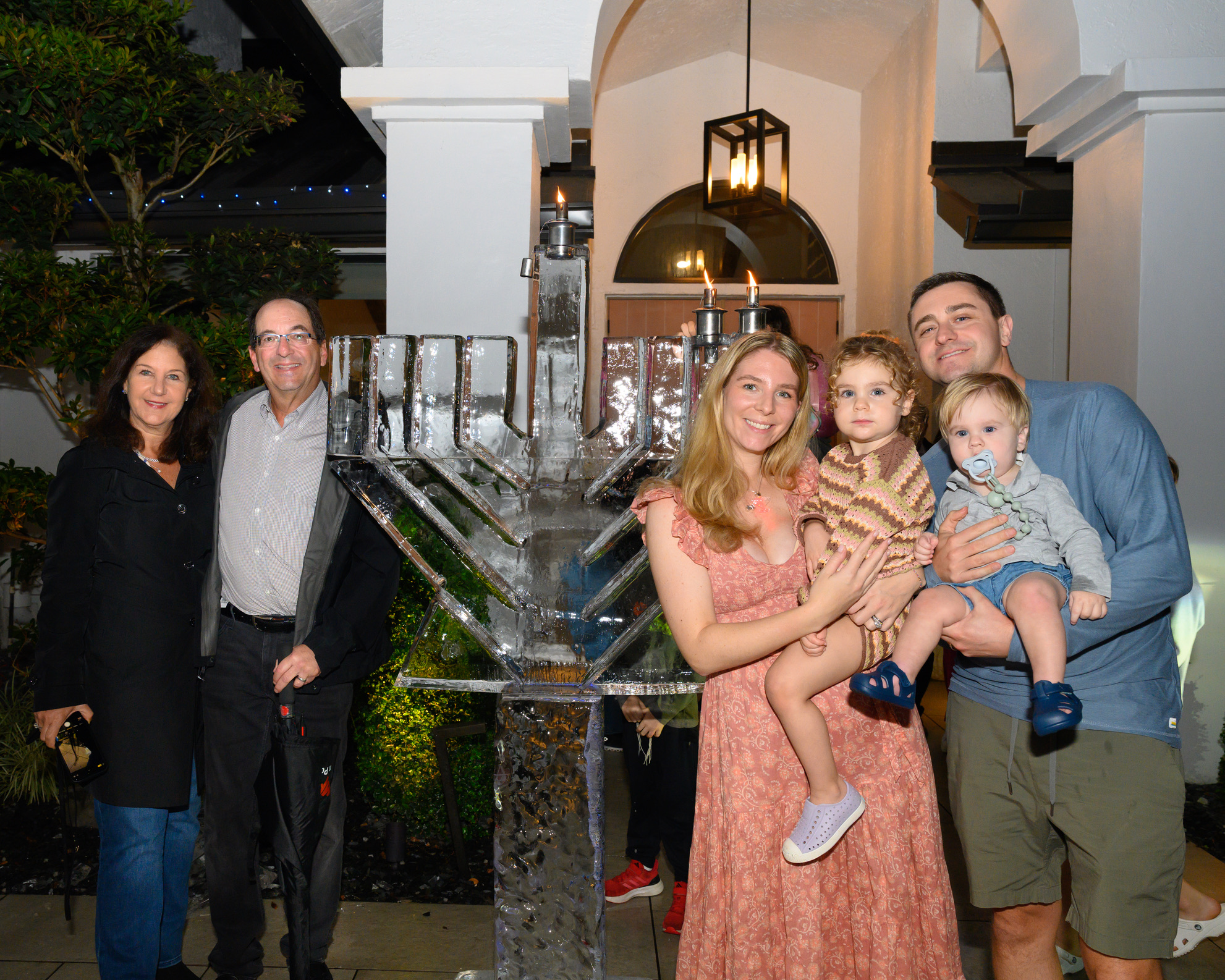 Three generations of a family celebrating Chanukah beside an ice menorah at Chabad Chai Center in Boca Raton