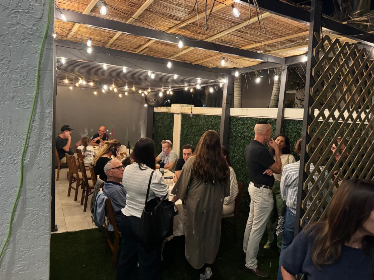 Friends sharing a festive evening together inside a sukkah